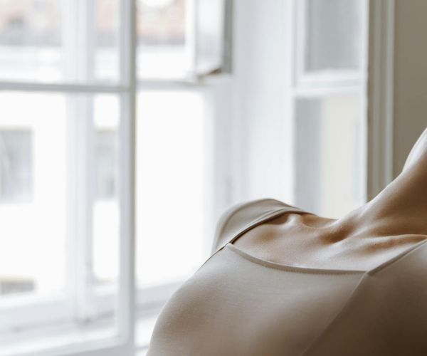 Person stretching gently near a window with soft morning light.